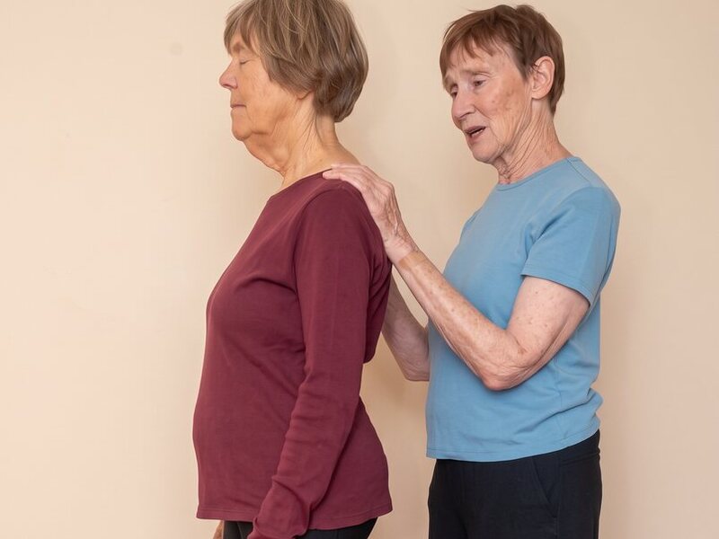 Somatic movement for forward head posture: Linda's hands resting on a student's shoulders