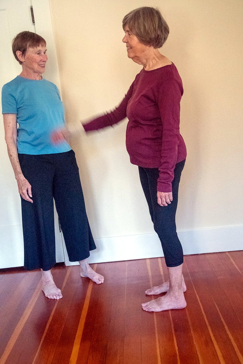 Linda and a student standing together in an open room, mid-movement