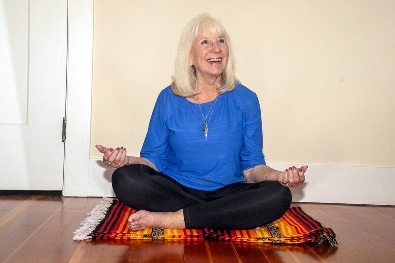 A Hanna Somatics student seated cross-legged on a mat, smiling mid-movement